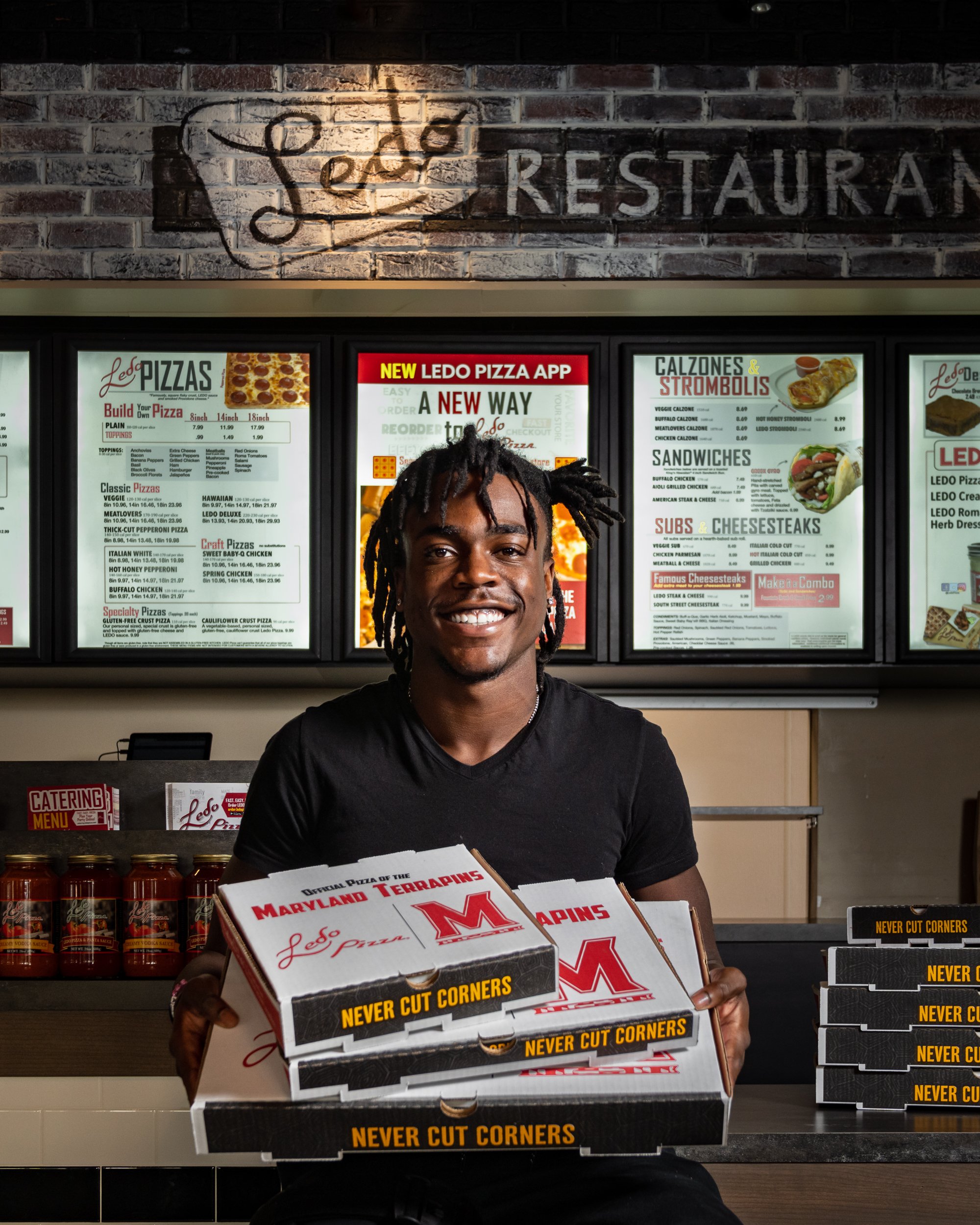 Ledo Pizza Partners with University of Maryland Wide Receiver Dontay Demus Jr. front counter holding boxes